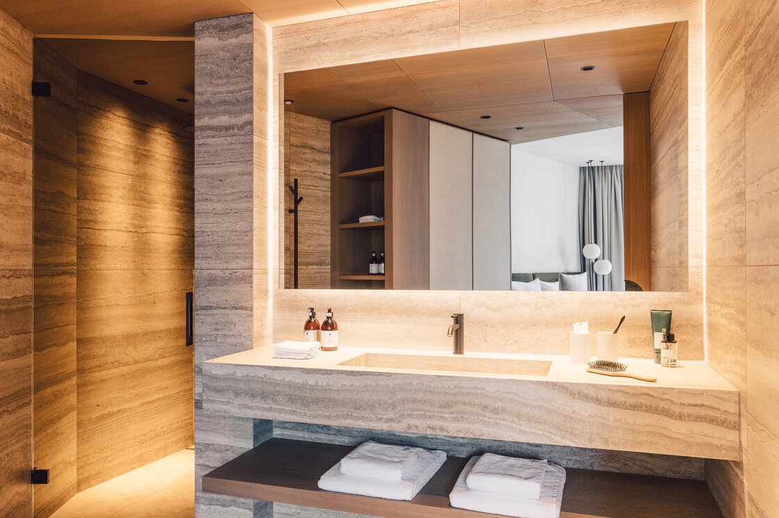Ein Badezimmer mit Naturstein, Doppelwaschbecken und großem Spiegel im Luxury Apartment.