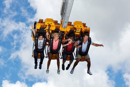 Vier Personen sitzen in einer Sky-Swing-Anlage vor dem Himmel und halten sich fest.