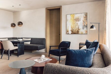 Ein moderner Wohn- und Essbereich mit Sofa, Sesseln, Esstisch und Wandkunst.