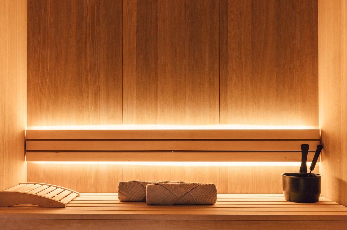 Eine Holzsauna mit Liegen und Aufgusseimer, warm beleuchtet im Apartment.