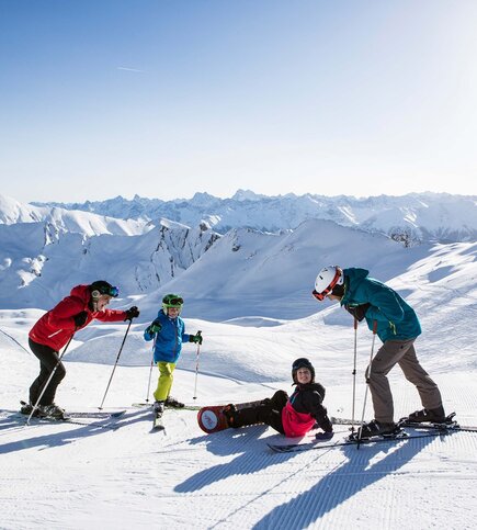 Eine Familie macht eine Pause beim Skifahren in der verschneiten Berglandschaft von Serfaus-Fiss-Ladis.