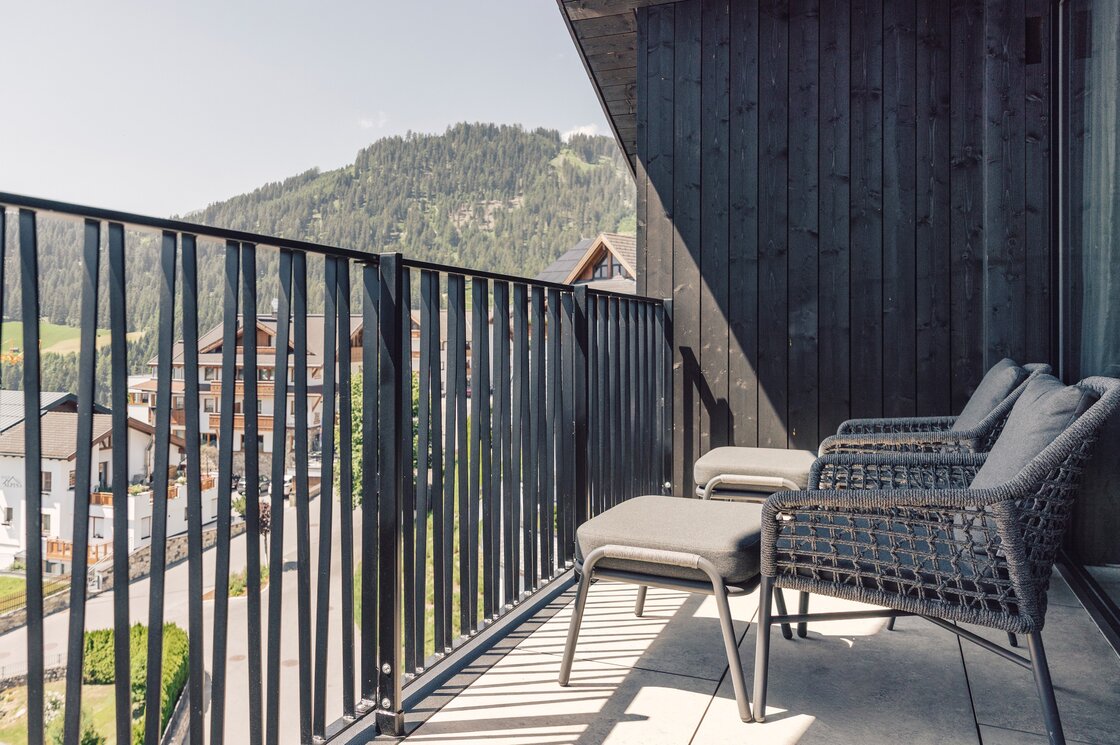 Ein Balkon mit Sitzbereich und Blick auf die Berge und Dächer in Fiss.