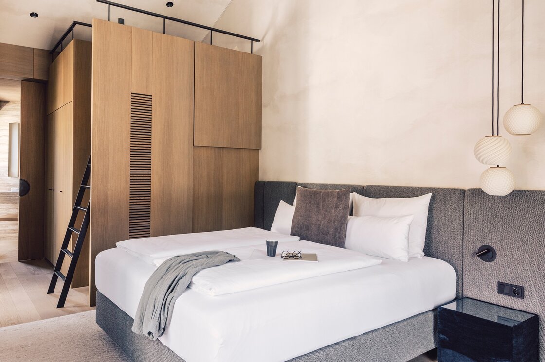 Ein modern eingerichtetes Schlafzimmer mit Doppelbett, Holzschrank und dezenter Beleuchtung.