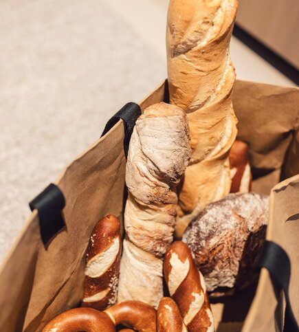 Verschiedene Brote und Baguettes liegen in einem Einkaufskorb.