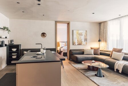 Ein offener Wohnbereich mit Kücheninsel, Esstisch und Ecksofa in einem modern eingerichteten Apartment.