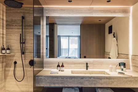 Modernes Badezimmer mit Regendusche, großem Spiegel und hellem Waschbereich in einem Apartment.