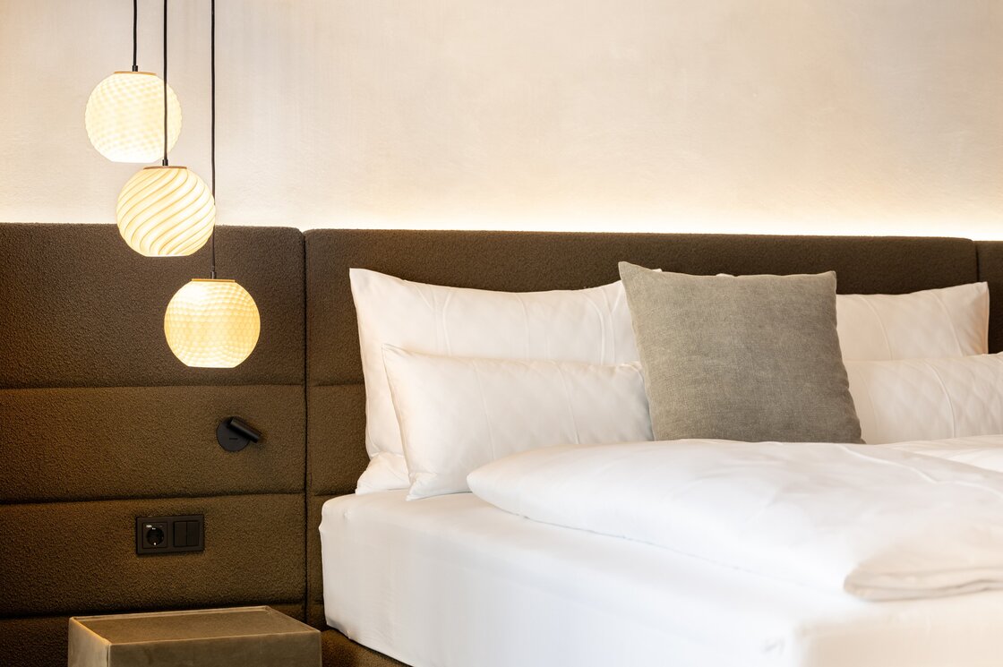 Ein modernes Schlafzimmer mit Doppelbett, gepolstertem Kopfteil und drei Hängelampen.