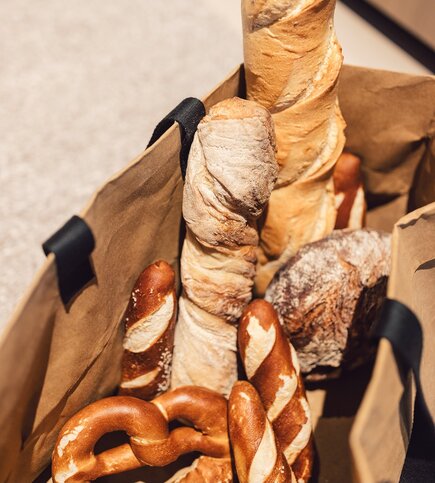 Different breads and pretzels are placed in a paper bag.