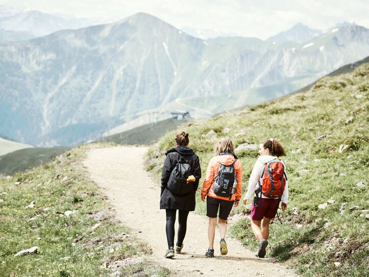 Wandergruppe auf Bergweg in Fiss Drei Wanderinnen gehen auf einem Bergweg durch die Alpen.