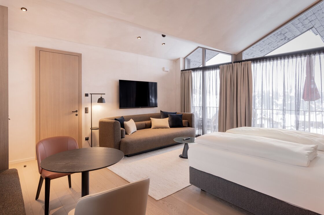 Der kombinierte Wohn- und Schlafbereich eines Penthouse mit Sofa, Bett und großen Fenstern.