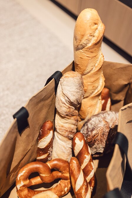 Ein Korb mit frischem Brot und Brezeln für das Frühstück steht auf einer Theke.
