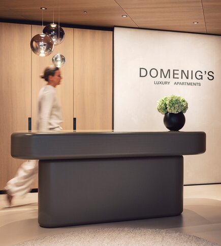 Eine Person geht am Empfangstresen von Domenig's Luxury Apartments vorbei.