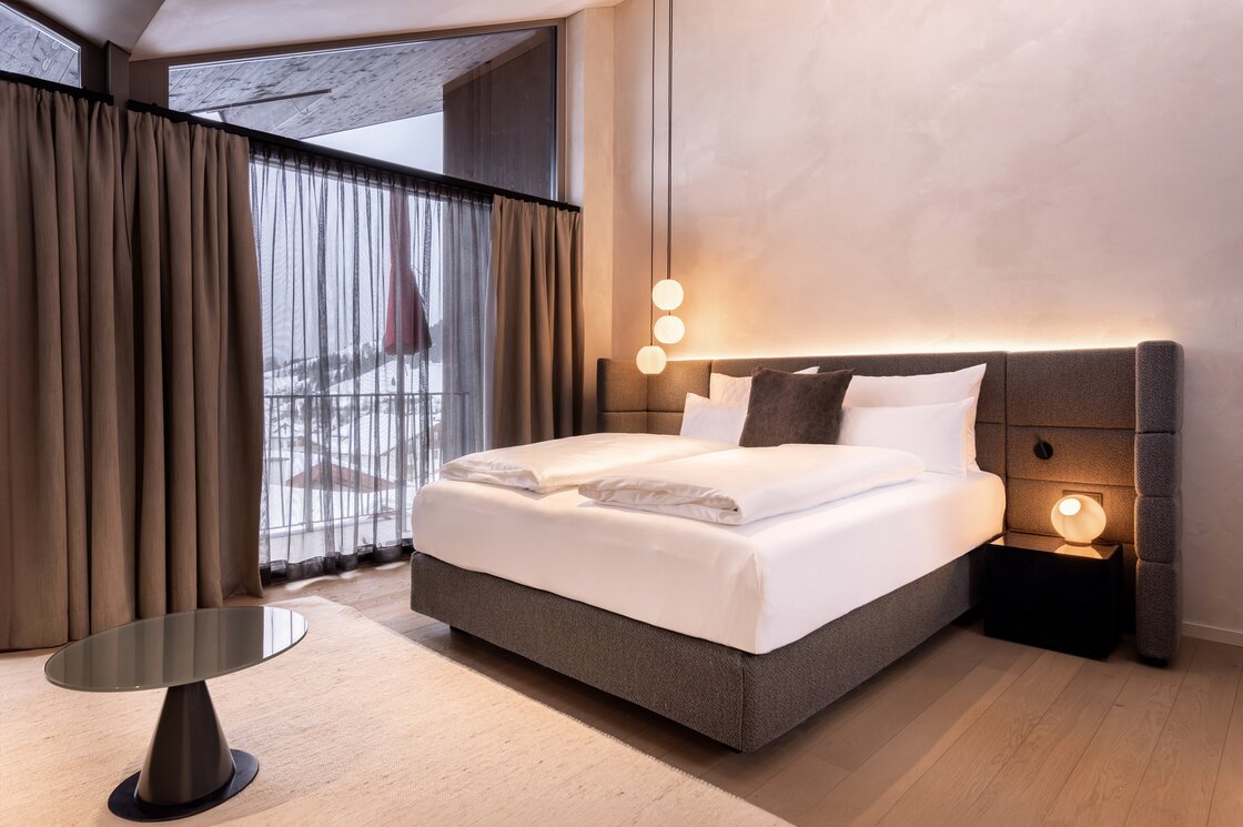 Ein modernes Schlafzimmer im Penthouse mit großem Bett und Blick auf die verschneiten Berge.