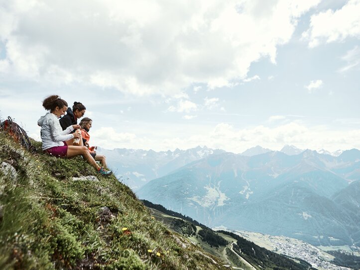 Wandern in Fiss mit Bergpanorama Drei Wanderinnen sitzen auf einer Bergwiese mit Blick ins weite Tal und auf die Alpen.