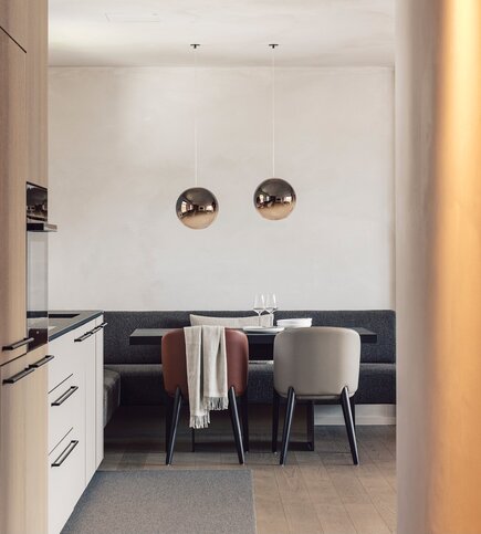 Ein moderner Essbereich mit Tisch, zwei Stühlen und Küchenzeile in einem Apartment.