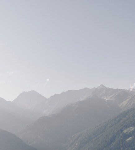 Blick auf eine Berglandschaft mit sanftem Dunst und klaren Gipfeln am Horizont.