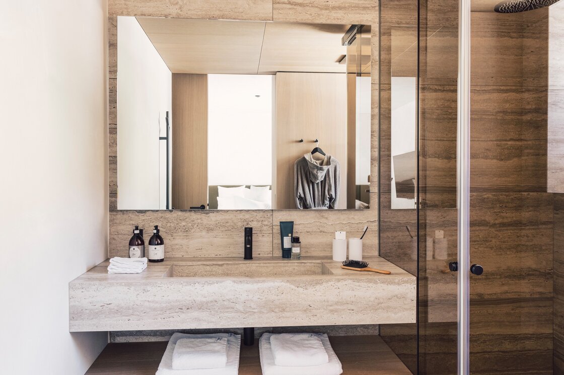Modernes Badezimmer mit Doppelwaschbecken, Spiegel, Dusche und Pflegeprodukten im Apartment.