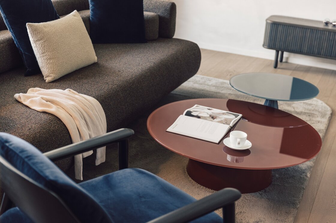 Ein moderner Wohnbereich mit Sofa, Couchtischen, Buch und Tasse in einem Apartment.