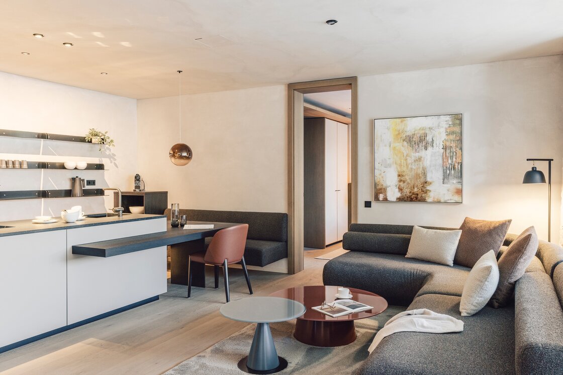 Wohn- und Küchenbereich eines modernen Apartments mit Sofa, Esstisch und offener Küche.