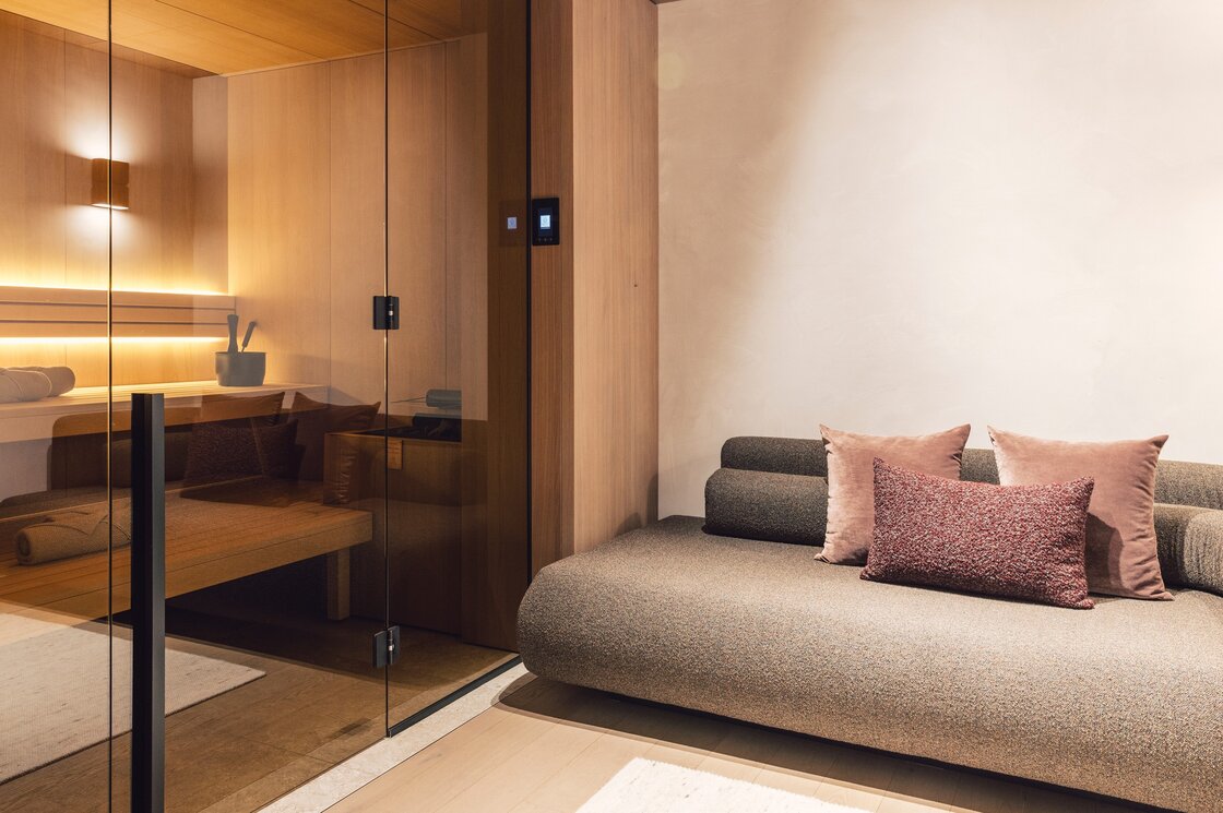 Eine private Sauna neben einer gemütlichen Sitzbank im Apartment mit warmen Holztönen.