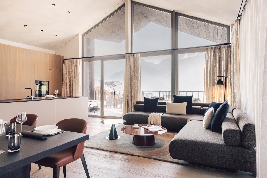 Der offene Wohnbereich des Penthouse zeigt große Fenster, eine Küche und Blick auf die Berge.