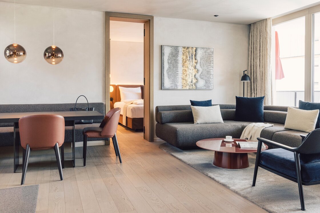 Heller Wohnbereich eines Luxury Apartment mit Sofa, Esstisch und offenem Durchgang zum Schlafzimmer.
