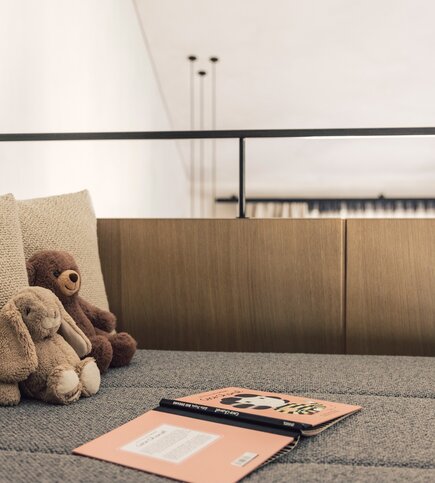 Auf der Schlafgalerie liegen drei Stofftiere neben einem offenen Buch auf dem Bett.