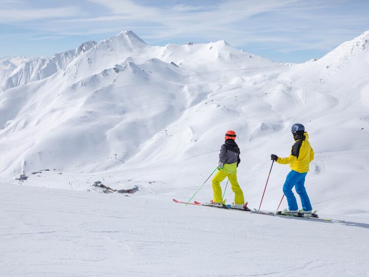 Skifahrer mit Bergblick in Serfaus-Fiss-Ladis Zwei Skifahrer stehen auf einer verschneiten Piste mit weitem Blick auf die Berge.