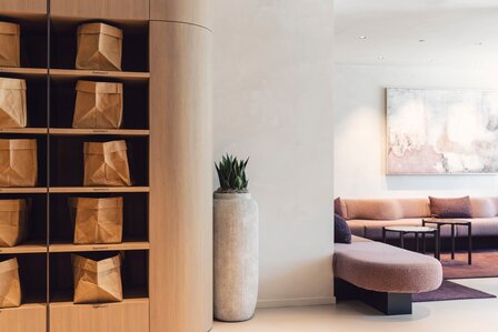 Ein moderner Wohnbereich mit offenen Regalen, Sitzbank, Sofa und einem Bild an der Wand.