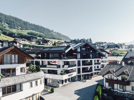 Mehrere Apartmenthäuser in Fiss vor grünen Hängen und einem hellen Himmel.