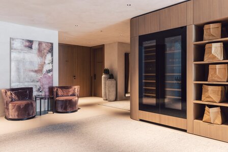 Ein moderner Loungebereich mit Samtsesseln, Kunst an der Wand und einem integrierten Weinkühlschrank.