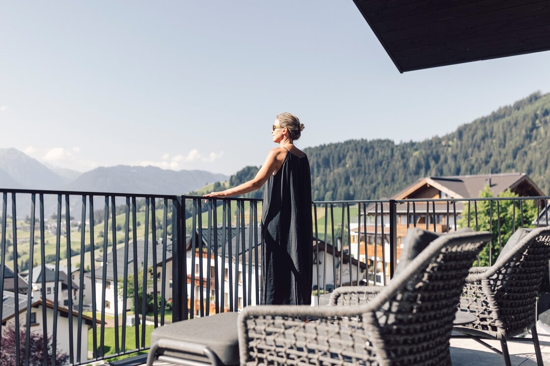 Eine Frau steht auf der Terrasse und blickt über die Berge bei Fiss.