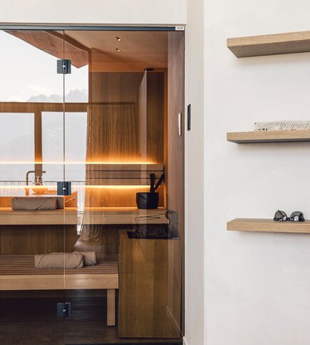 Ein moderner Saunabereich mit Holz, Glasfront und warmem Licht in einem Apartment.