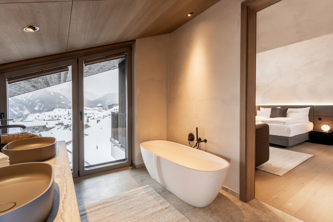 Ein modernes Badezimmer mit freistehender Badewanne und Blick auf die verschneiten Berge.