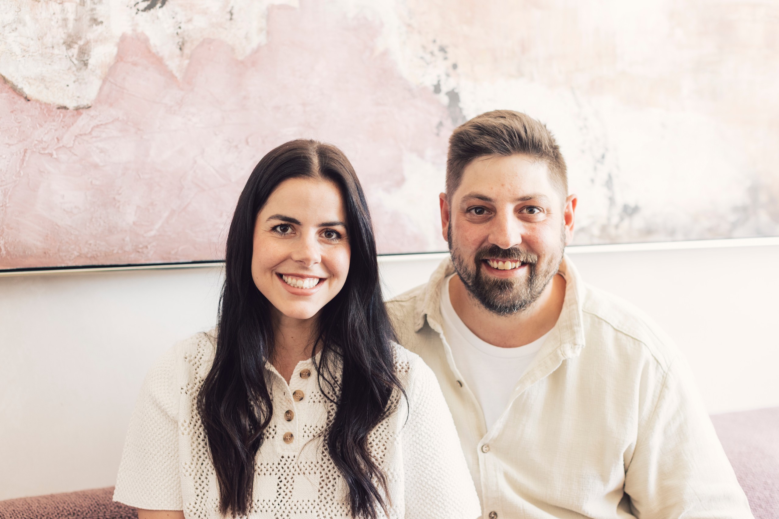 Magdalena Domenig and a man smile in front of a light-colored wall in the house.