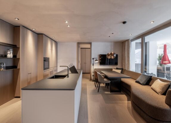 Appartement Fiss 2, Übersicht Wohnbereich mit Couch und Küchenzeile, Blick auf den großen Balkon