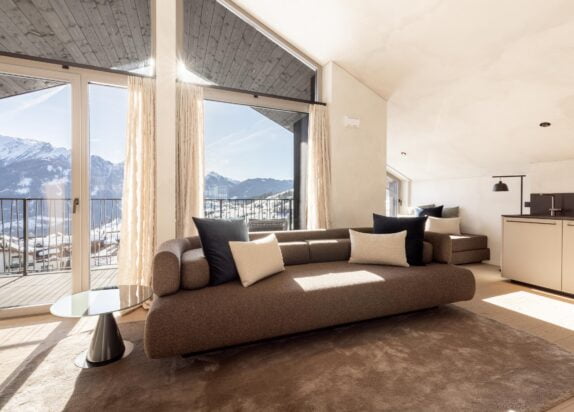 Luxus Ferienwohnung Penthouse 2, Wohnbereich mit großem Sofa und Kissen, grauer Teppich, große Fenster mit Zugang zum Balkon