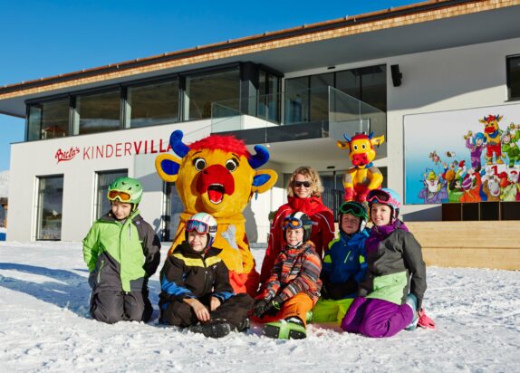 Ski holidays with children, Berta's children's villa building, children and mascot Berta in the foreground