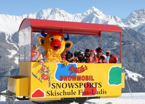 Skigebiet für Familien, Berta's Snowmobil, Kinder winken aus Anhänger