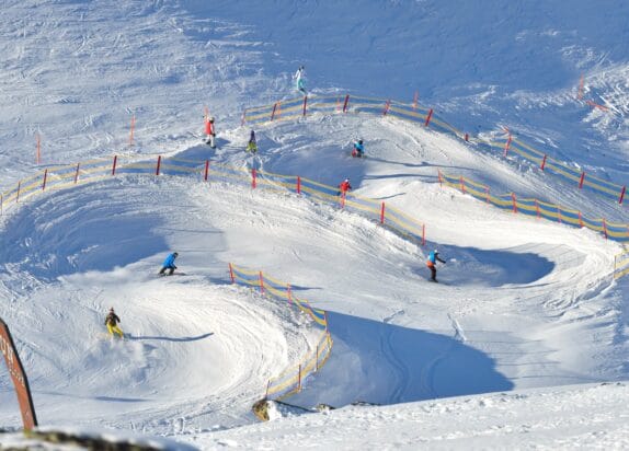 Skiurlaub mit Kinder, Ski und Snowboarder fahren durch eine Fun Slope