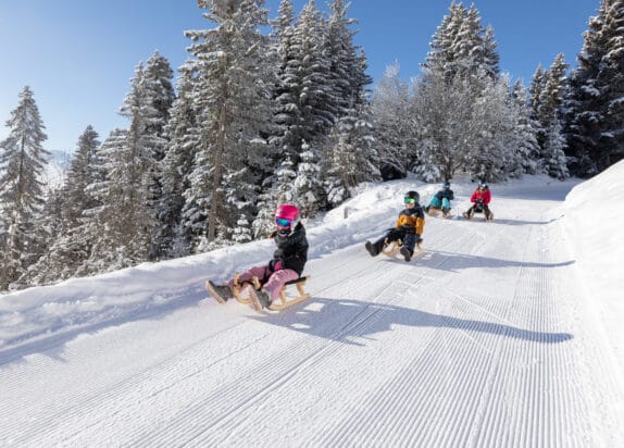 Witches toboggan run Fiss, four children tobogganing on a freshly prepared toboggan run