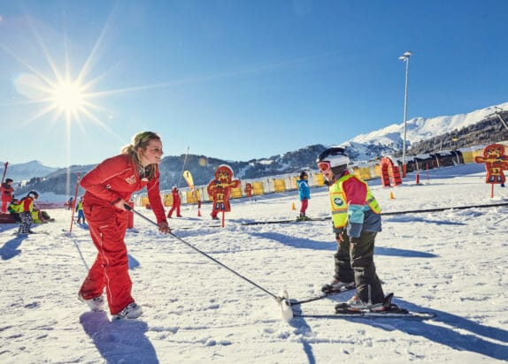 Family ski holiday, child takes a ski course, ski instructor pulls the child