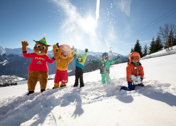 Skigebiet für Familien, Maskottchen Murmli und Berta spielen mit Kindern im Schnee