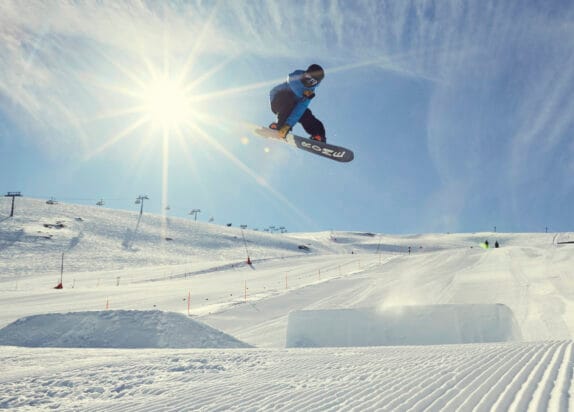 Fun park in the Fiss ski resort, snowboarder jumps over kickers