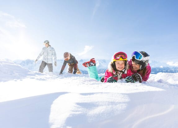 Fiss ski resort, skiing holiday with children, mum and child lying in the snow, dad and son in the background