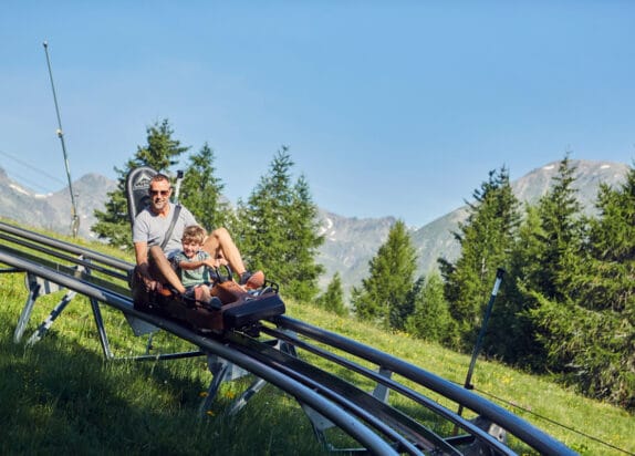 Familienurlaub in den Bergen - Sommerrodelbahn, Papa mit Sohn