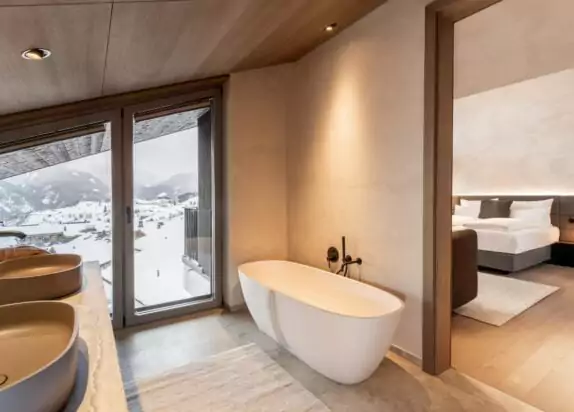 Appartement Fiss Penthouse 3, Bad mit großer Badewanne, zwei Waschbecken und Blick ins Schlafzimmer