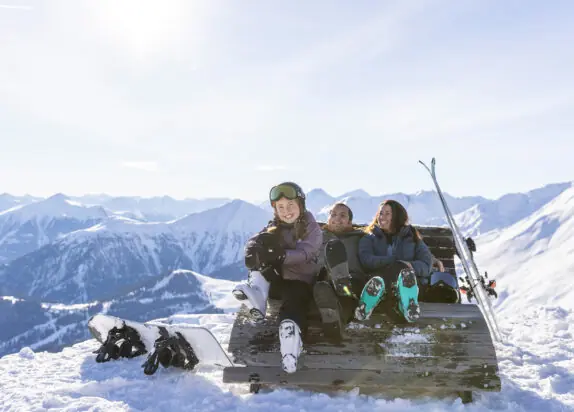 Skifahren mit Kindern Österreich, Familie im Schnee mit Berge im Hintergrund